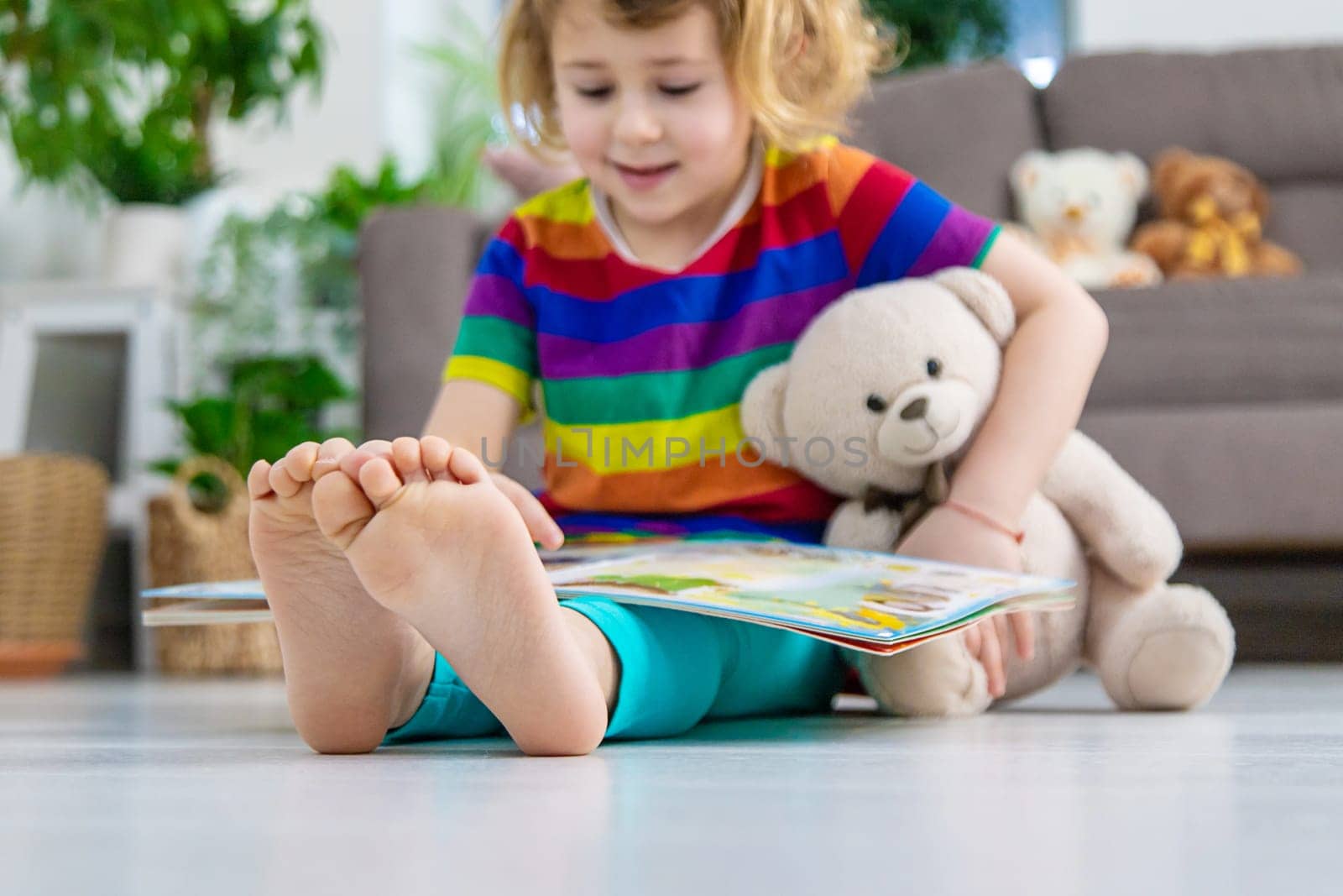 Child reading a book at home with a teddy bear at home. Selective focus. kid.
