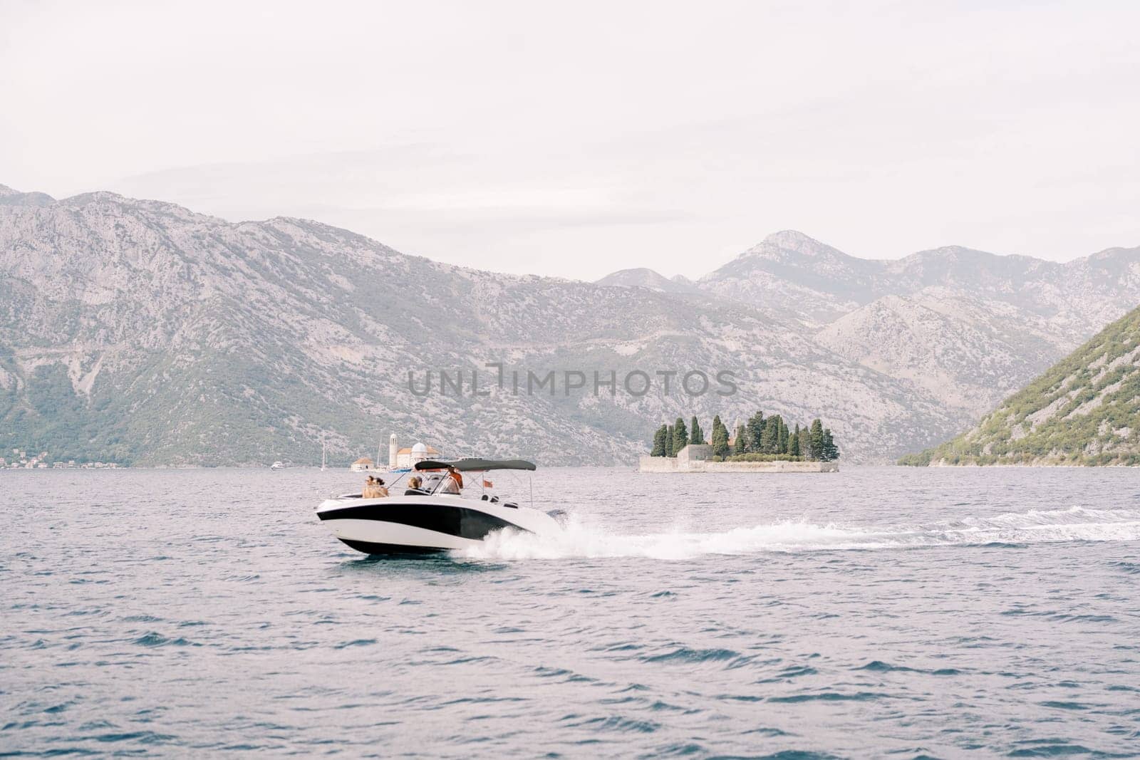 Motor yacht sails along the Bay of Kotor with the islands in the background. Montenegro. High quality photo