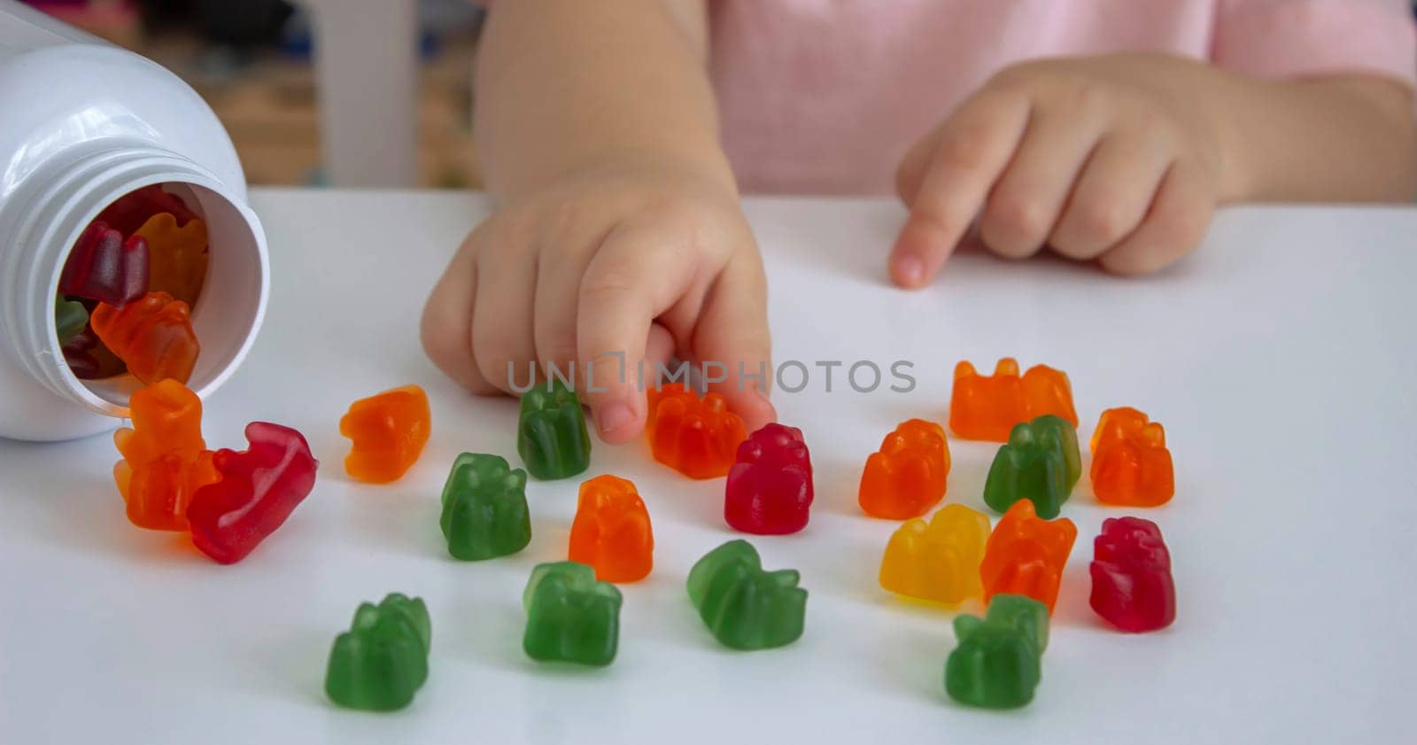 Little girl eating jelly candies or vitamins. child.