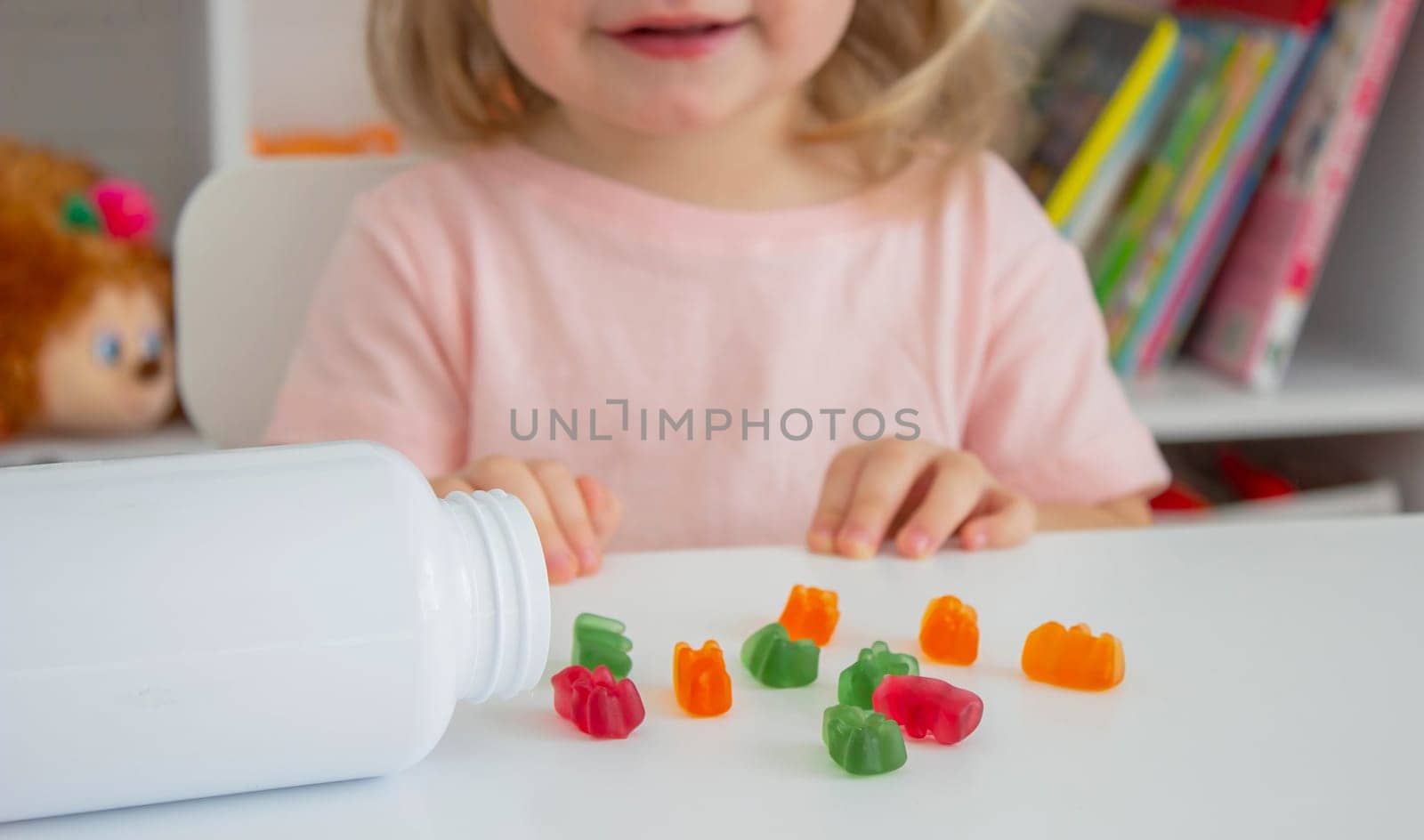 Little girl eating jelly candies or vitamins. child.