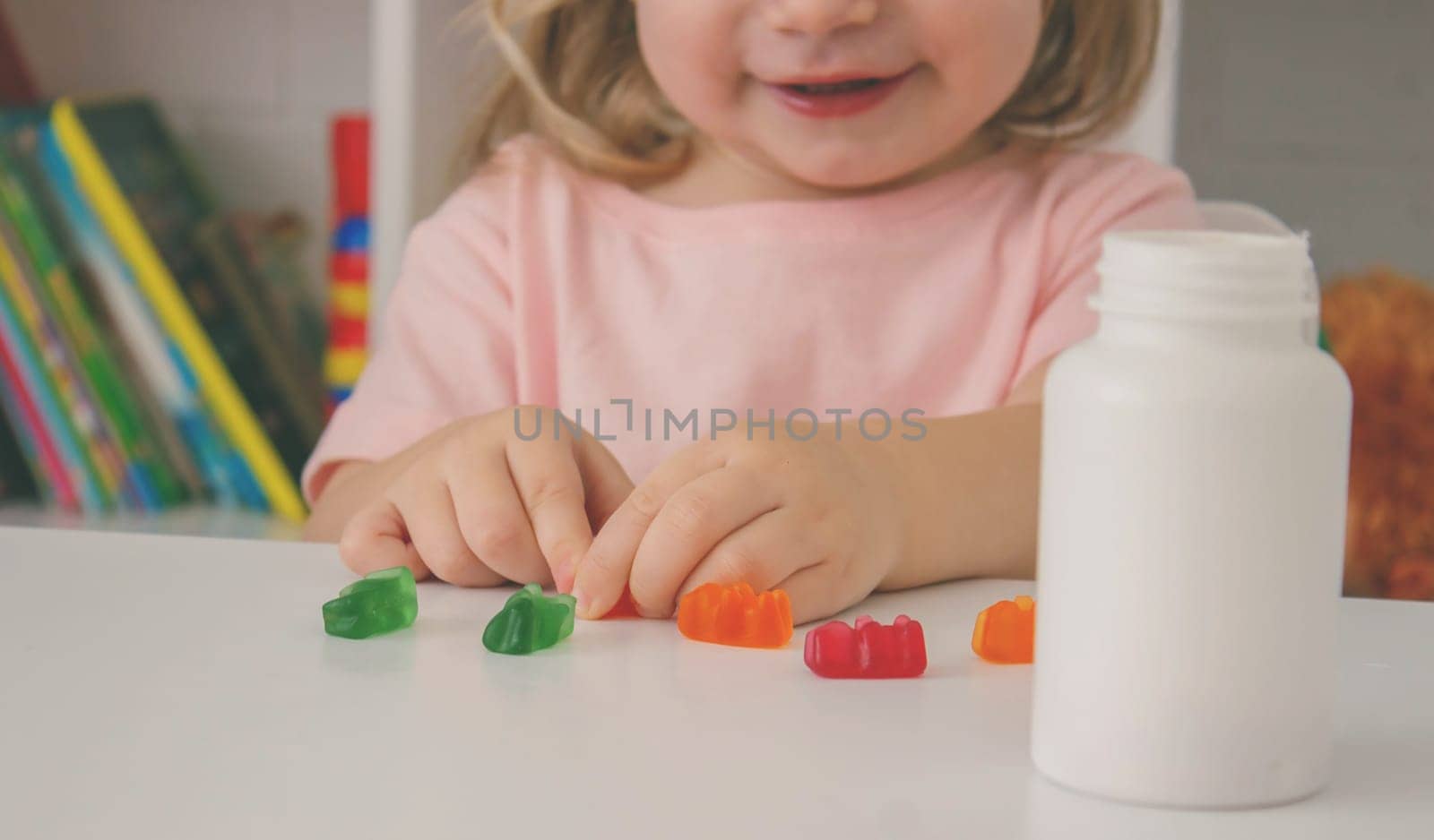 Little girl eating jelly candies or vitamins. child.