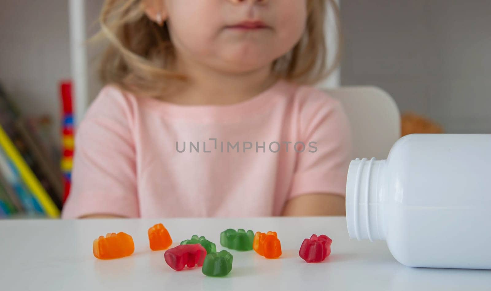 Little girl eating jelly candies or vitamins. child.