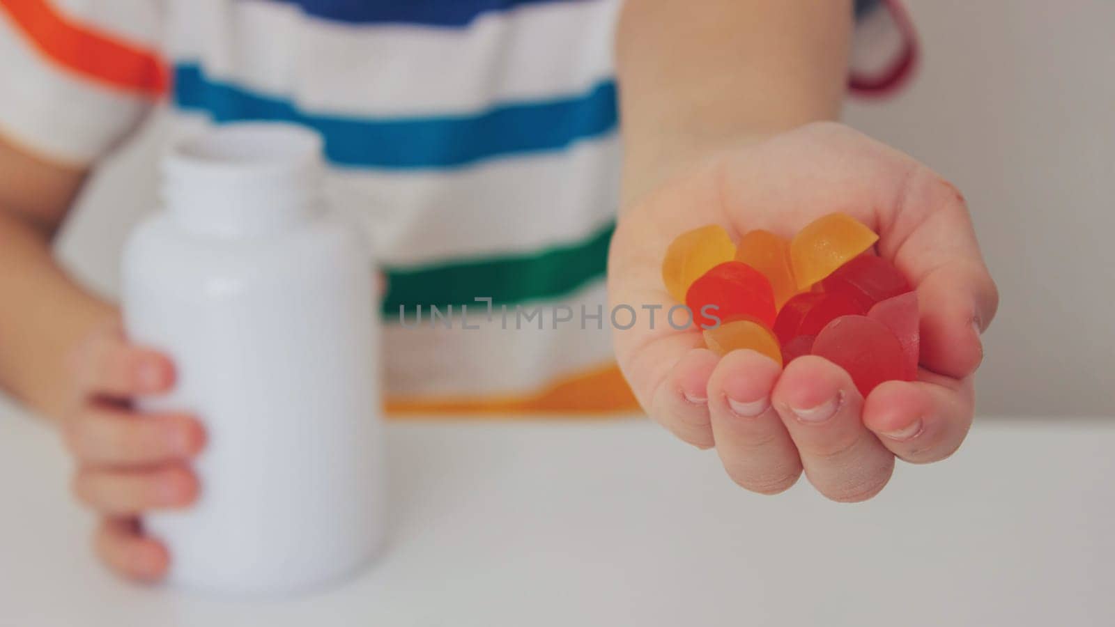 The boy eats jelly beans or takes vitamins.