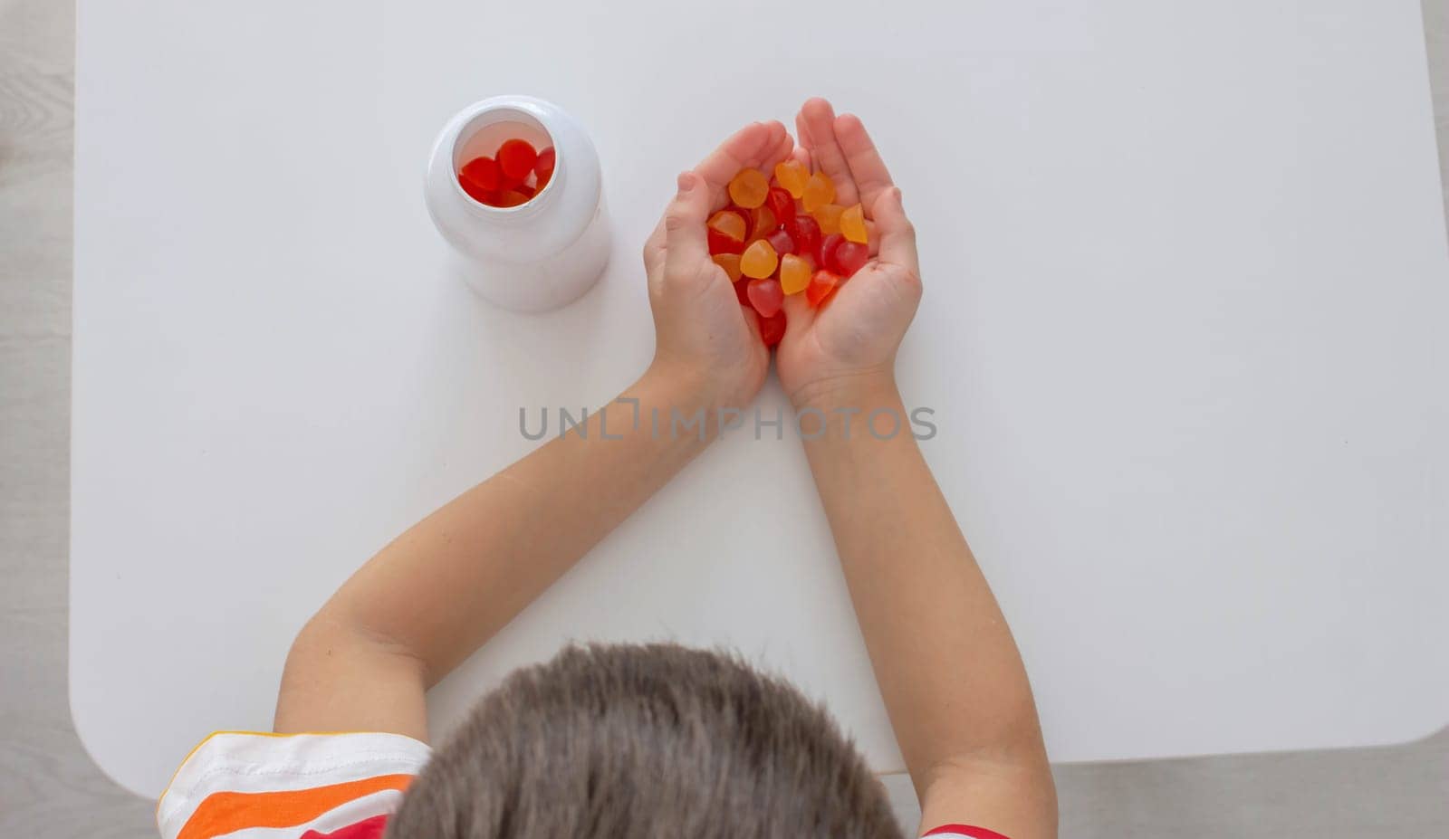 The boy eats jelly beans or takes vitamins.