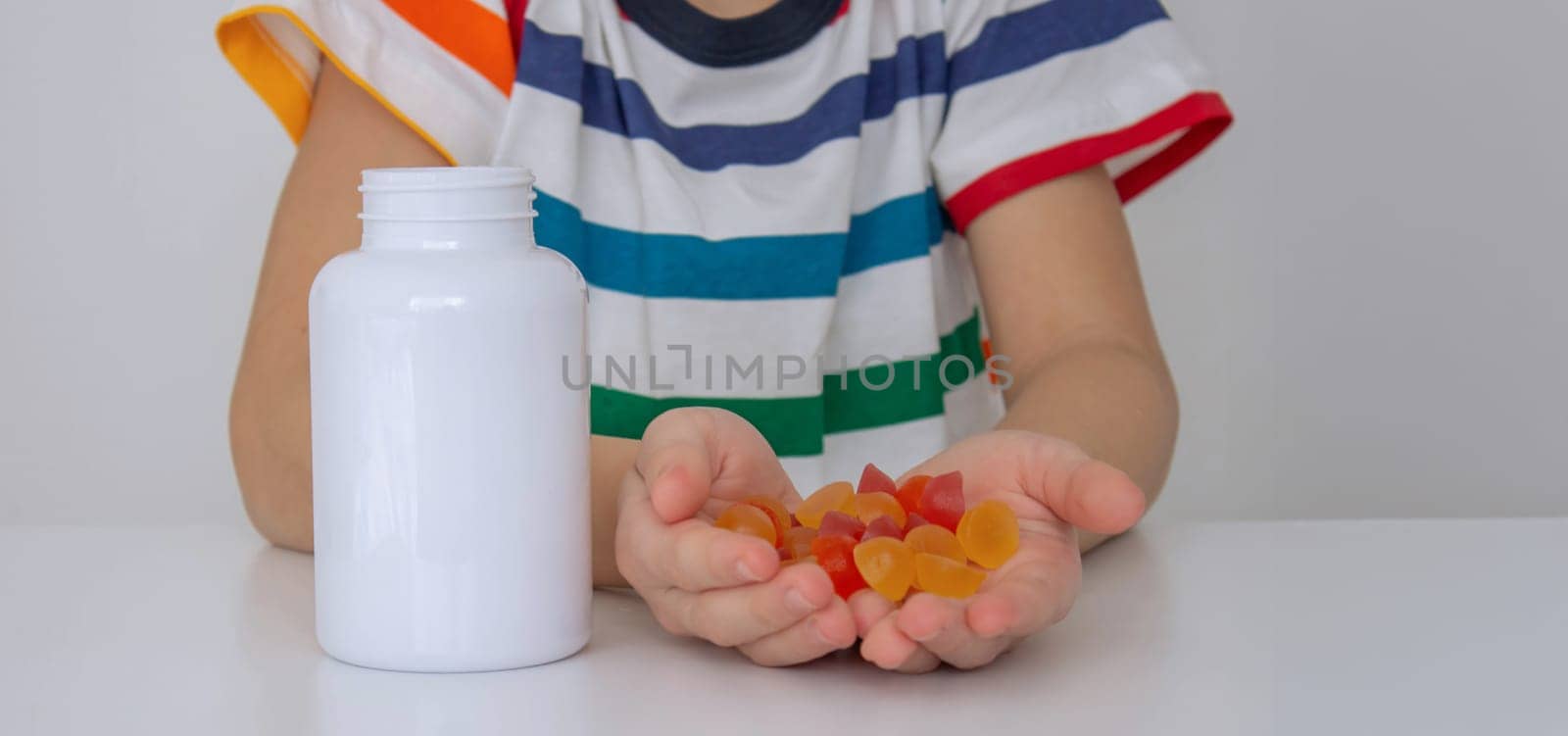 The boy eats jelly beans or takes vitamins.