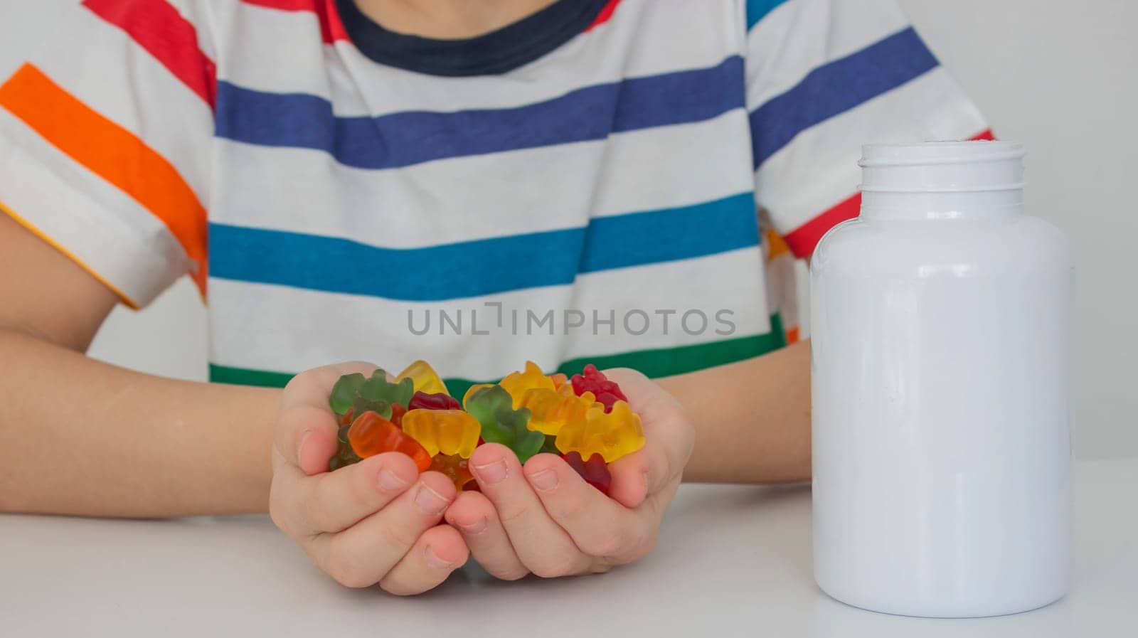 The boy eats jelly beans or takes vitamins.