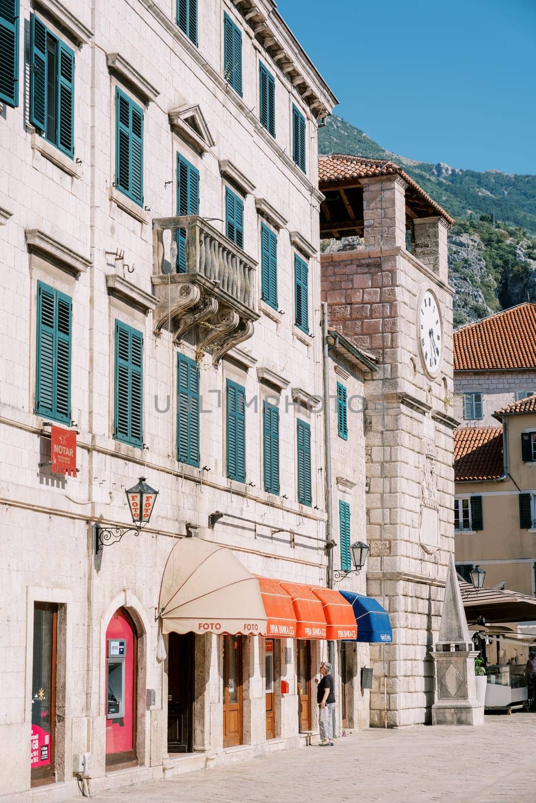 Old stone building with colorful coverings near the ancient clock tower. Kotor, Montenegro. High quality photo