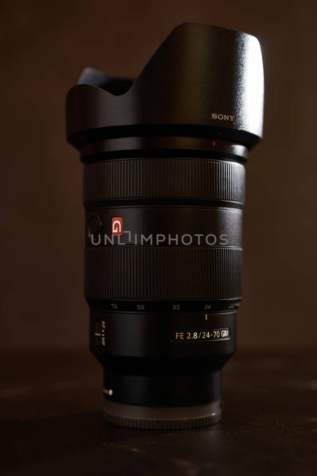 Replacement lens Sony FE 24-70mm for the camera stands on a black table. High quality photo