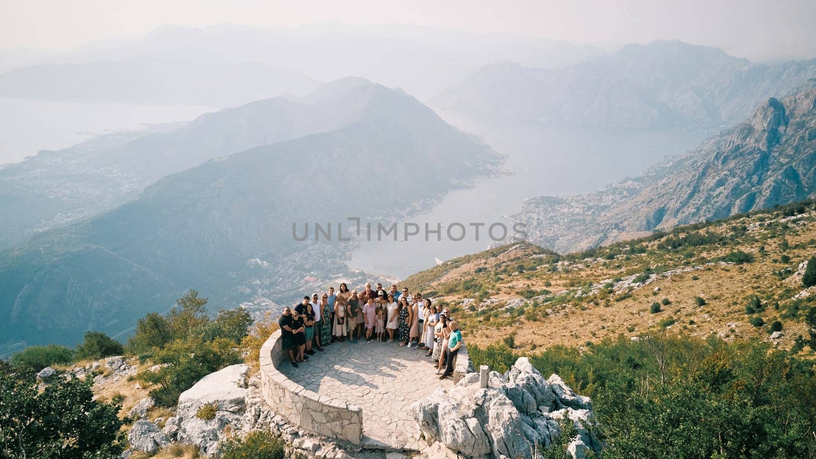 Group of tourists stands on an observation deck on a mountain above the Bay of Kotor. Montenegro. Drone. High quality photo