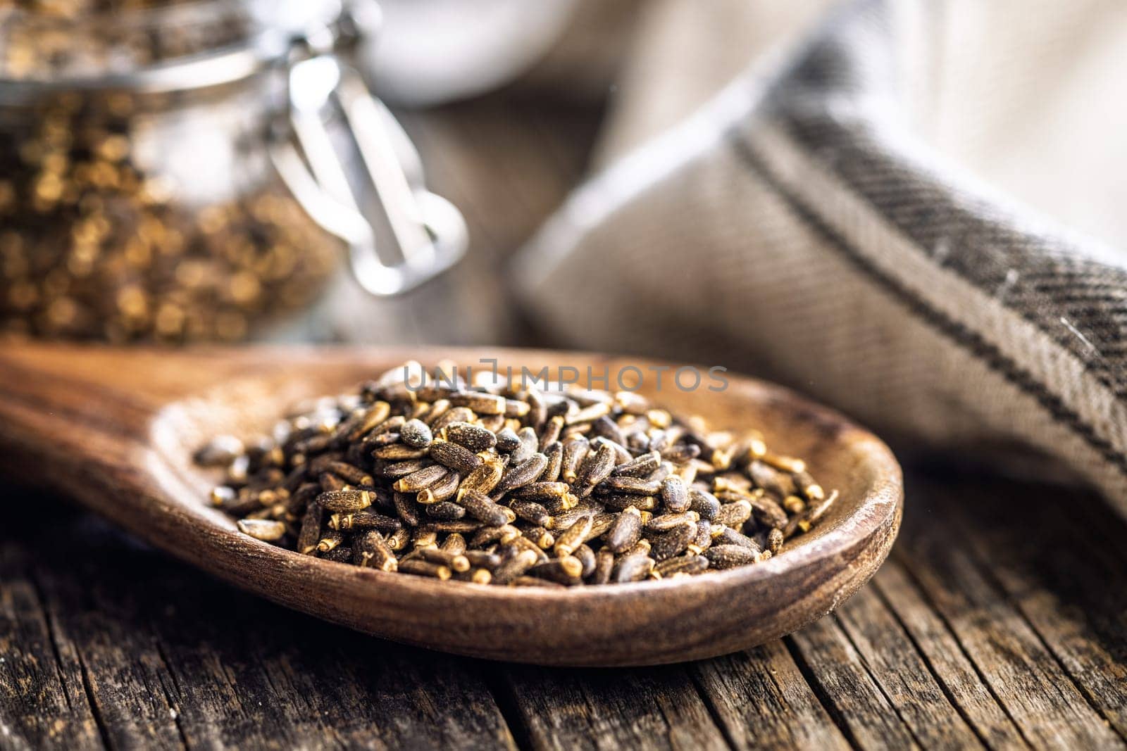 Milk thistle seeds on wooden spoon on a wooden table.