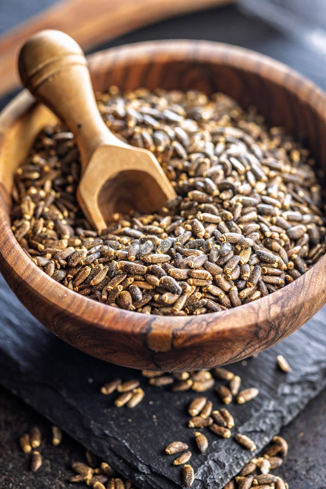 Milk thistle seeds in bowl on a black table.