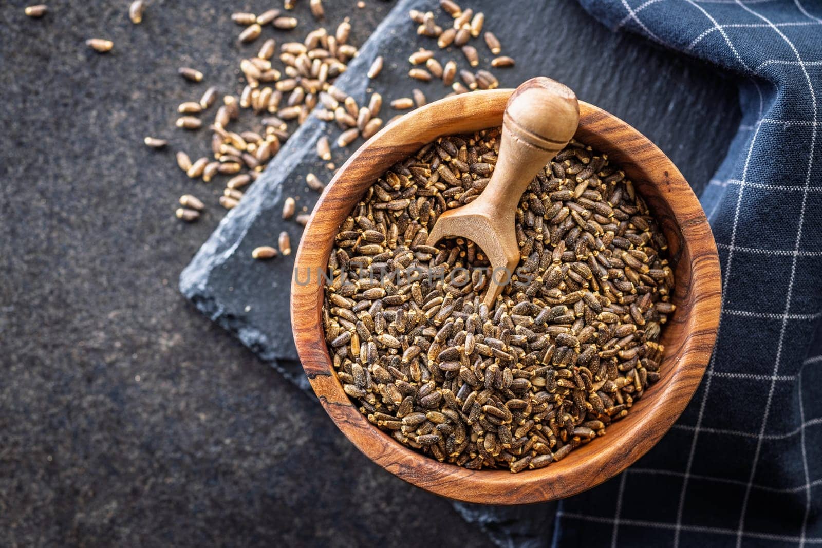Milk thistle seeds in bowl on a black table. Top view.