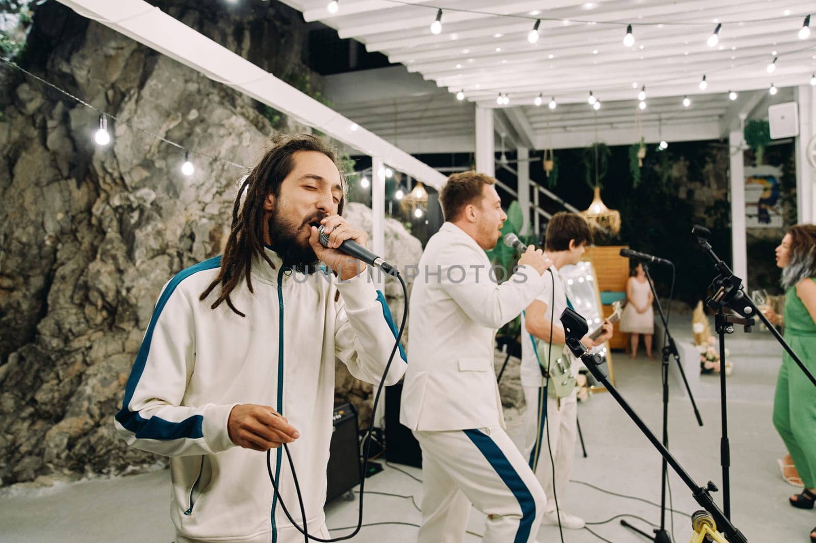 Musical group performs on stage under a canopy with glowing garlands of light bulbs. High quality photo