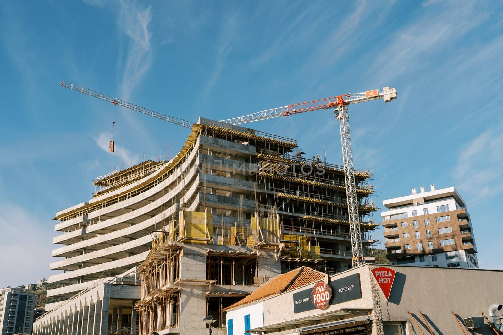 High tower cranes work at the construction site of a multi-storey building. High quality photo