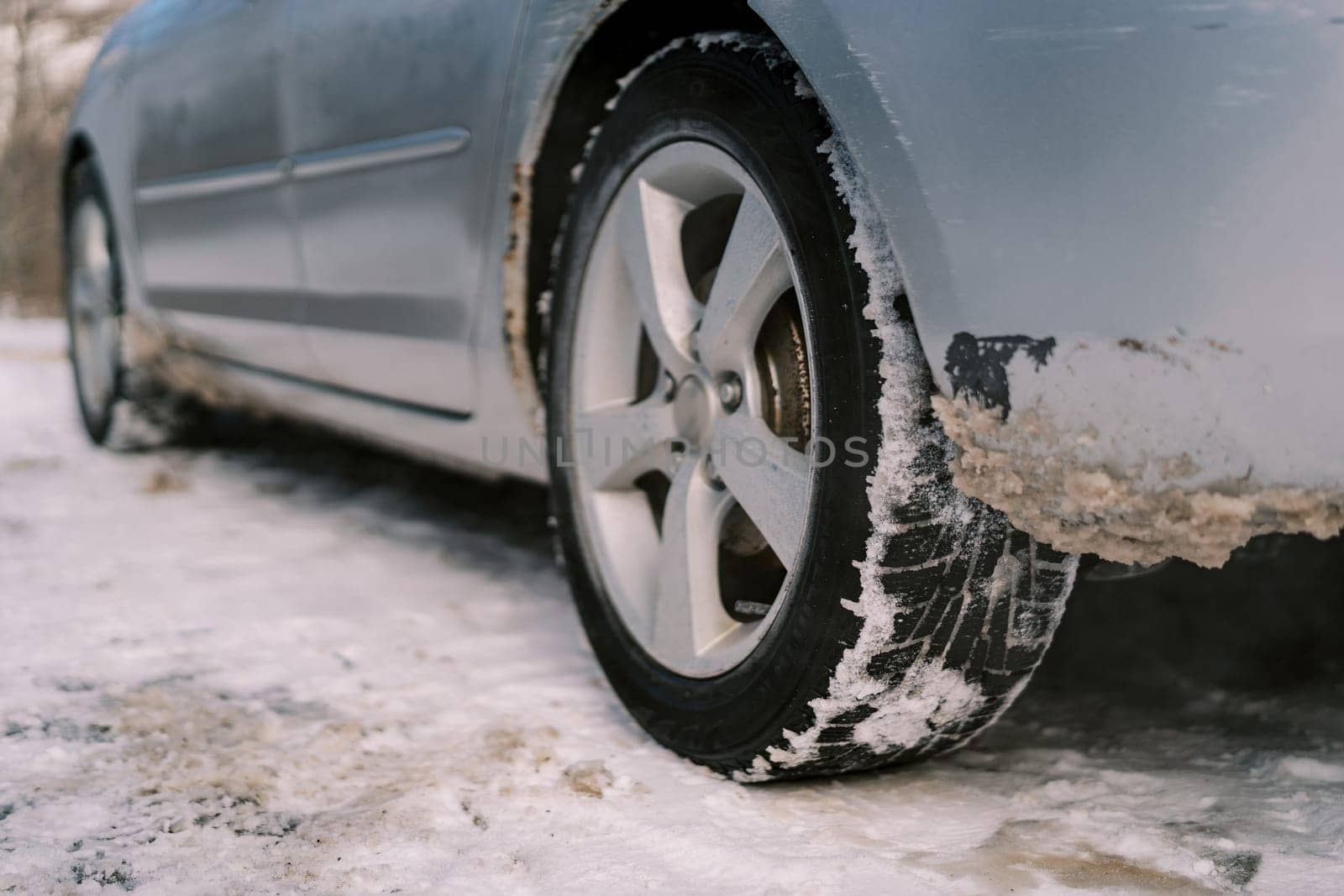 Back of the car with dirty snow near the wheel and under the body. High quality photo