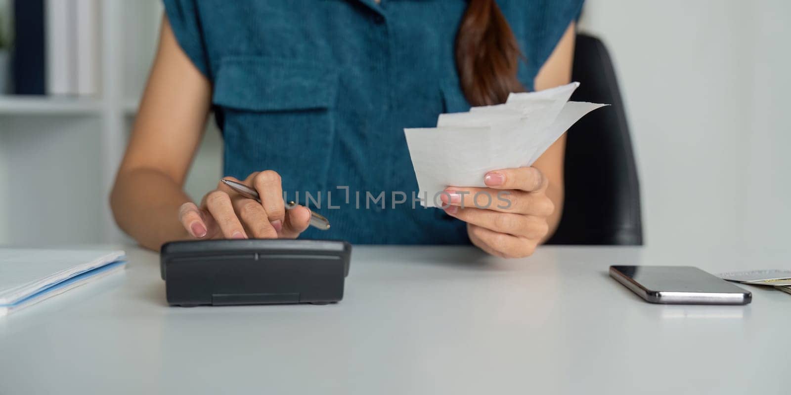 A woman takes her budgeting seriously, engaging with a calculator and reviewing receipts as she tracks her expenses for better financial insights.