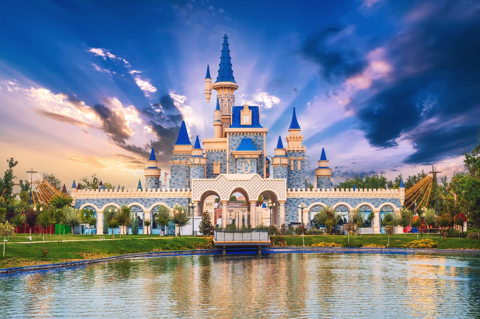 Beautiful fantastic fairy tale castle by lake at Magic City amusement Park in Tashkent in Uzbekistan at sunset