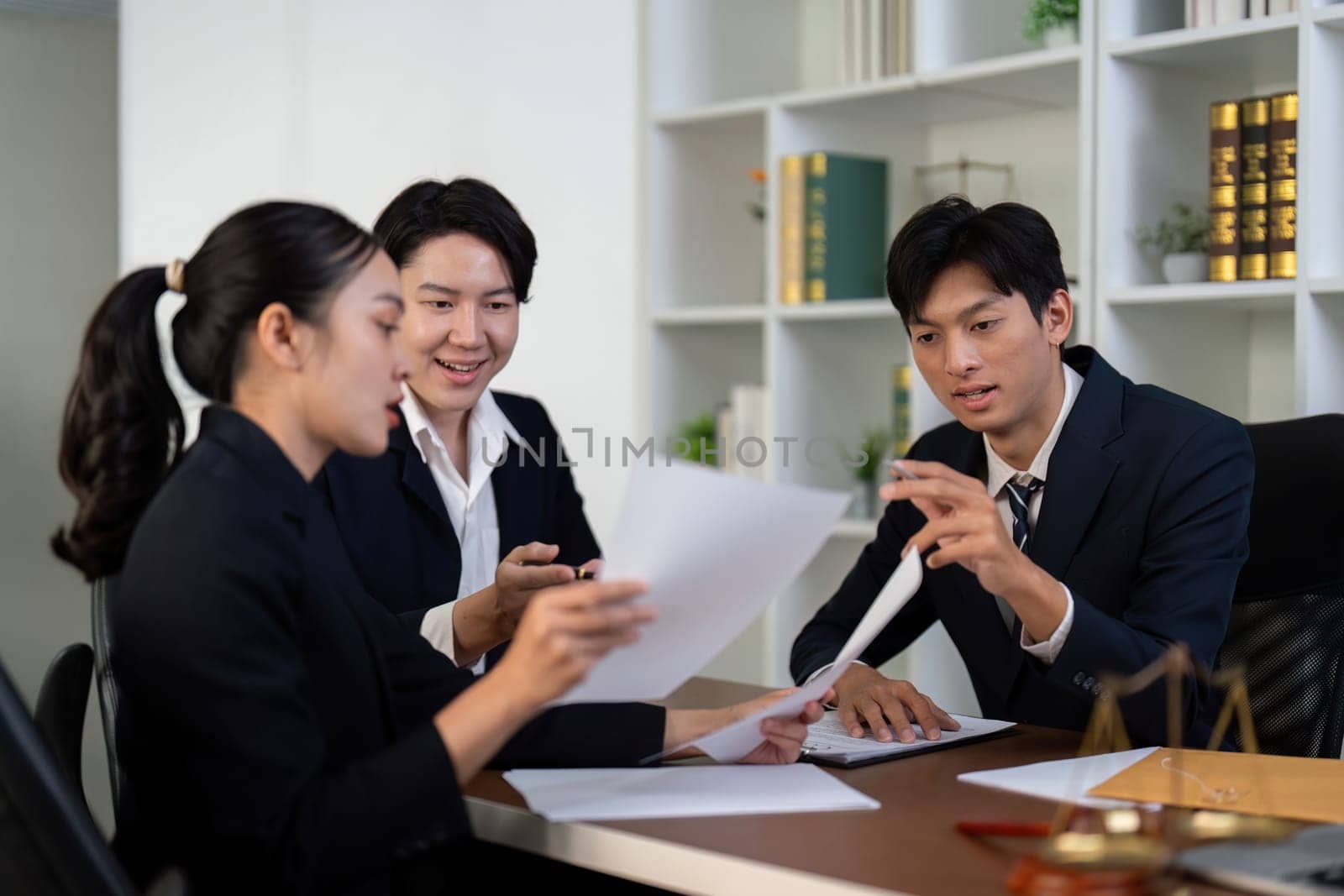 A group of lawyers reviews important documents together, discussing strategies and sharing insights for their legal cases in a professional office setting.