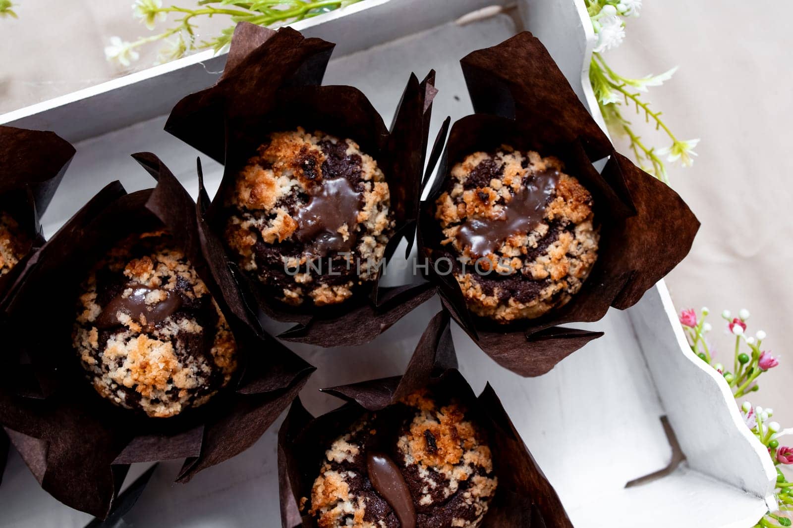 Delicious chocolate muffins with crumb topping in decorative brown wrappers.