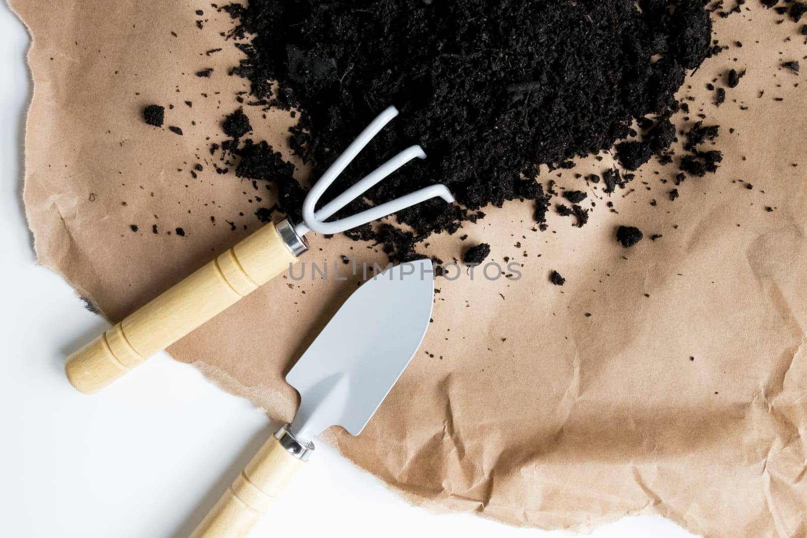 Gardening tools with soil on brown paper background.