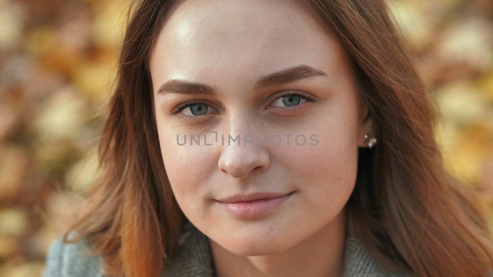Portrait of a young and beautiful girl against a background of yellow leaves. Face close up