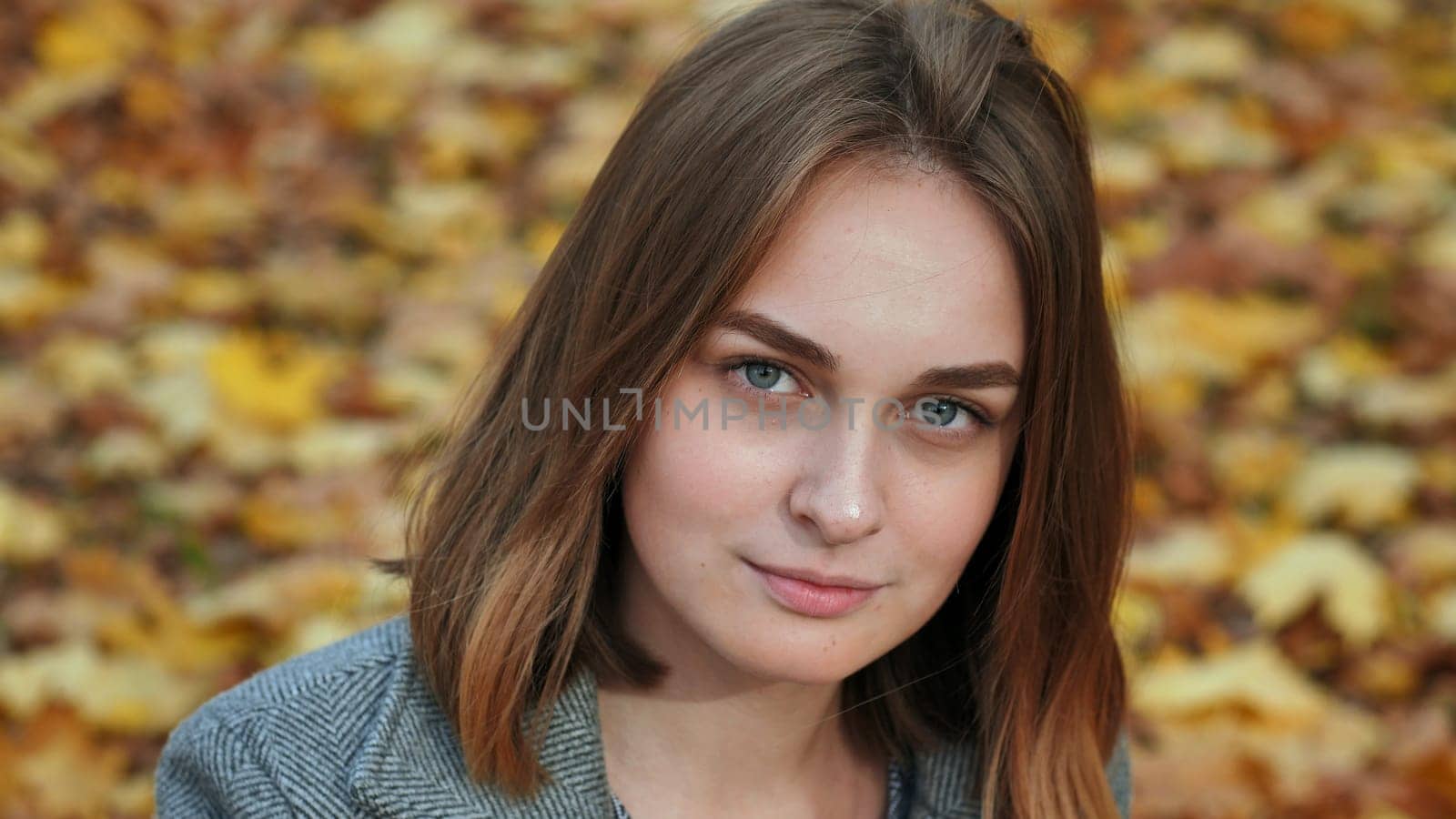 Portrait of a young and beautiful girl against a background of yellow leaves. Face close up
