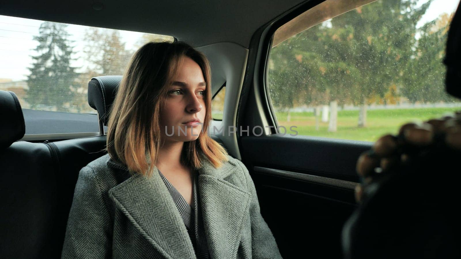 A sad young girl drives in a car salon in the fall