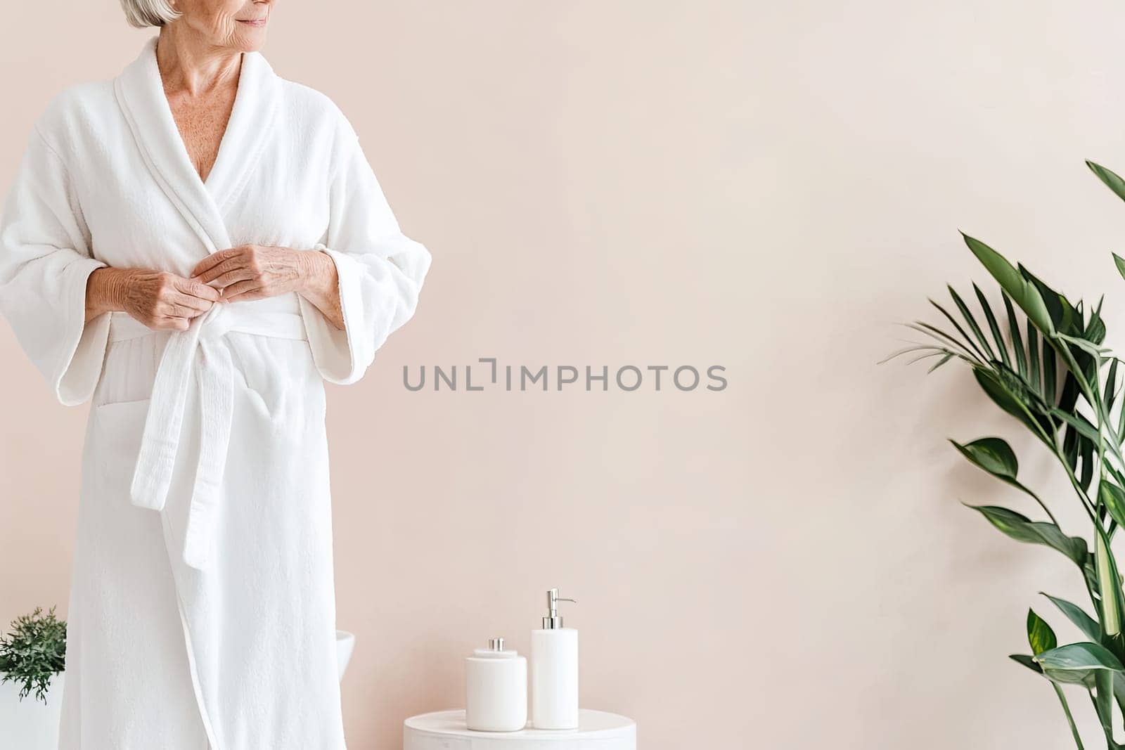 An elderly woman lies comfortably on her back in a calming spa environment as a beautician applies a soothing white mask to her face with a brush. Soft light illuminates the serene atmosphere, enhancing relaxation.