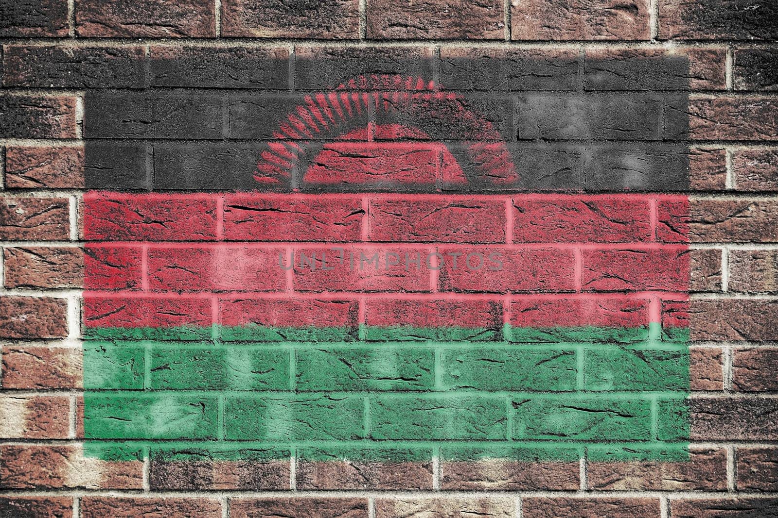 A Malawi flag on old brick wall background rising sun red green black