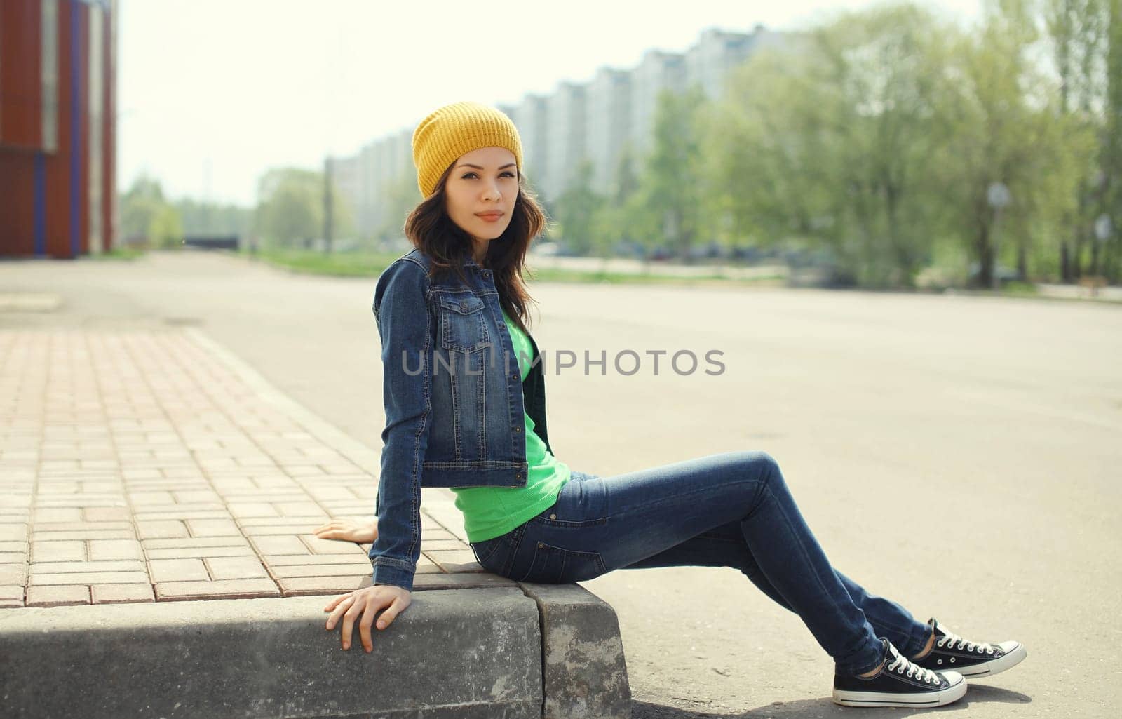 Beautiful brunette young woman in hat, jacket posing on city street
