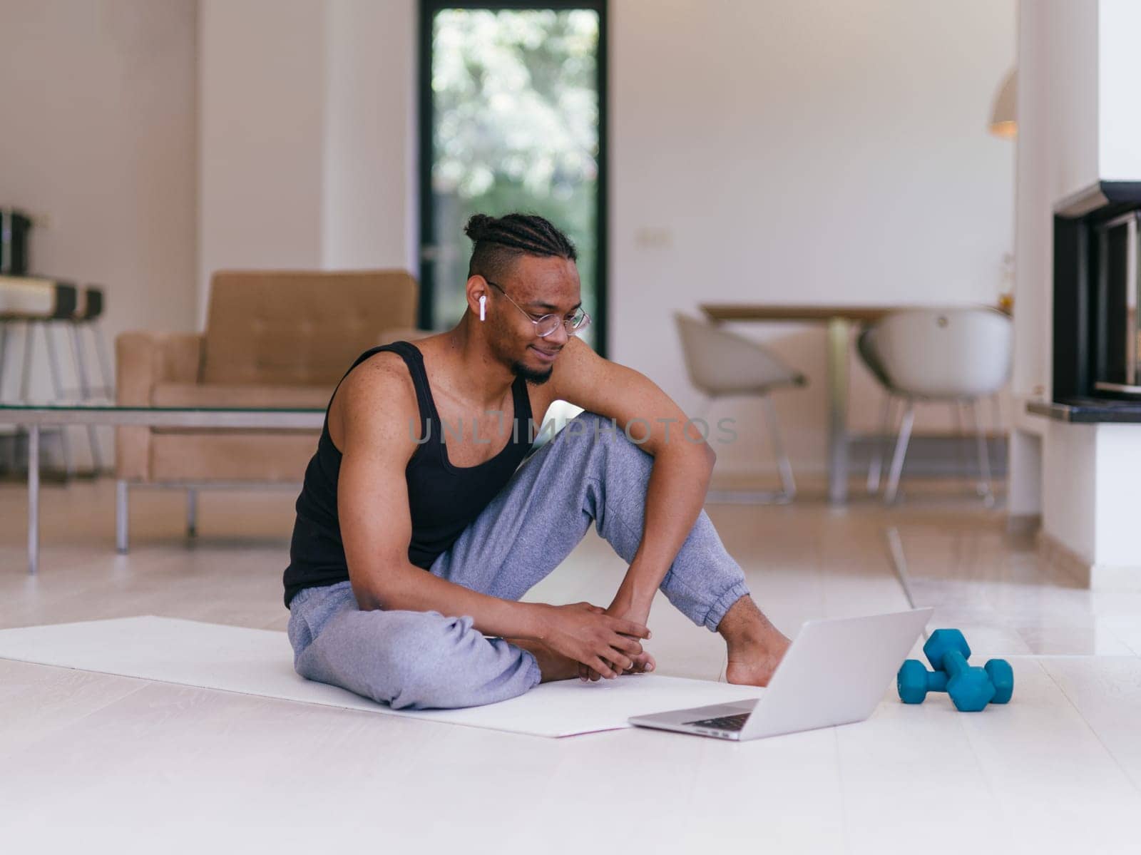 Training At Home. Sporty man doing the training while watching an online tutorial on a laptop, exercising in the living room, free space