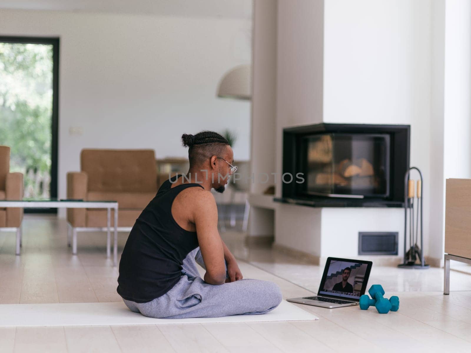 Training At Home. Sporty man doing the training while watching an online tutorial on a laptop, exercising in the living room, free space