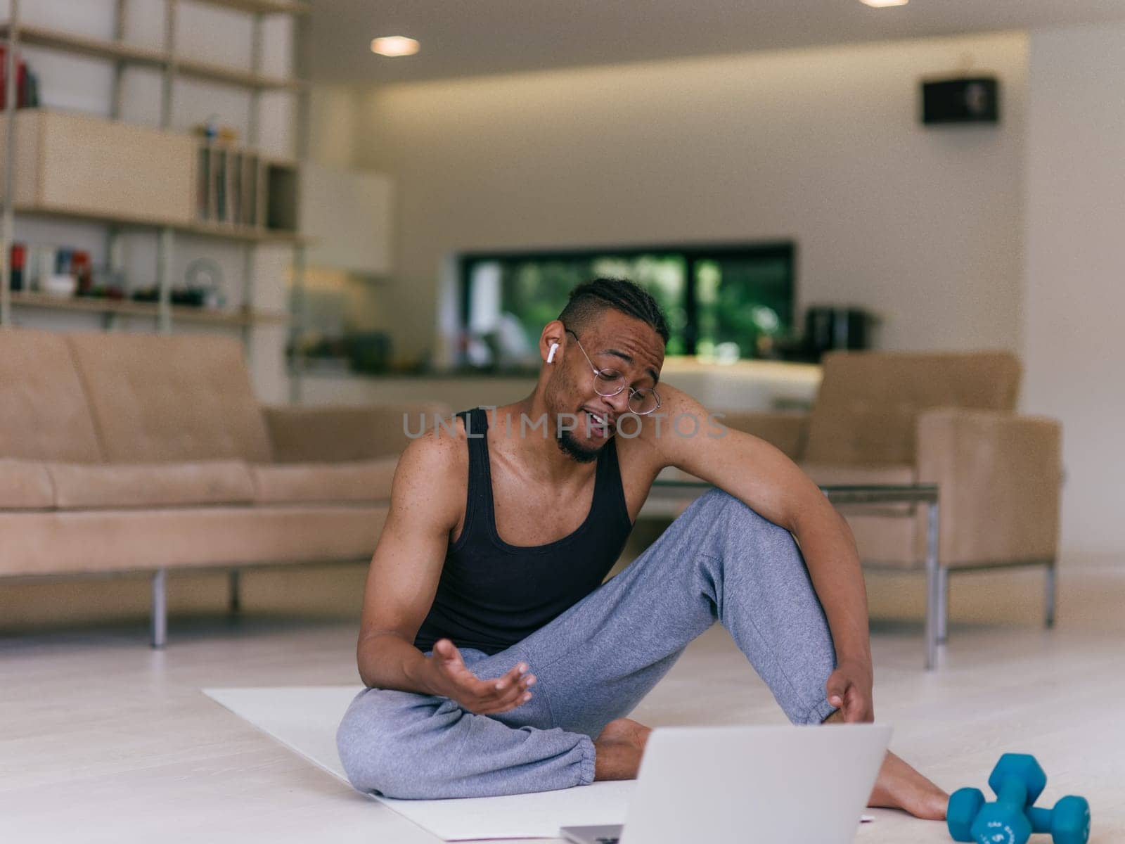 Training At Home. Sporty man doing the training while watching an online tutorial on a laptop, exercising in the living room, free space