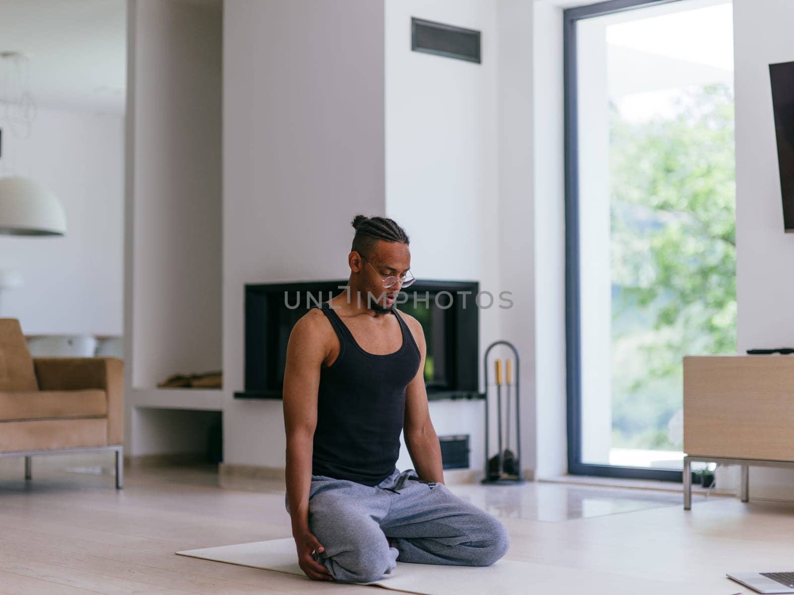 Training At Home. Sporty man doing the training while watching an online tutorial on a laptop, exercising in the living room, free space