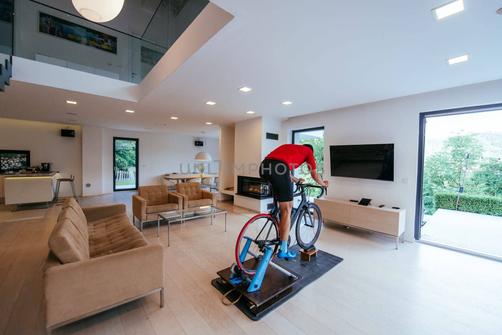 A triathlete riding a triathlon bike on a machine simulation in a modern living room.