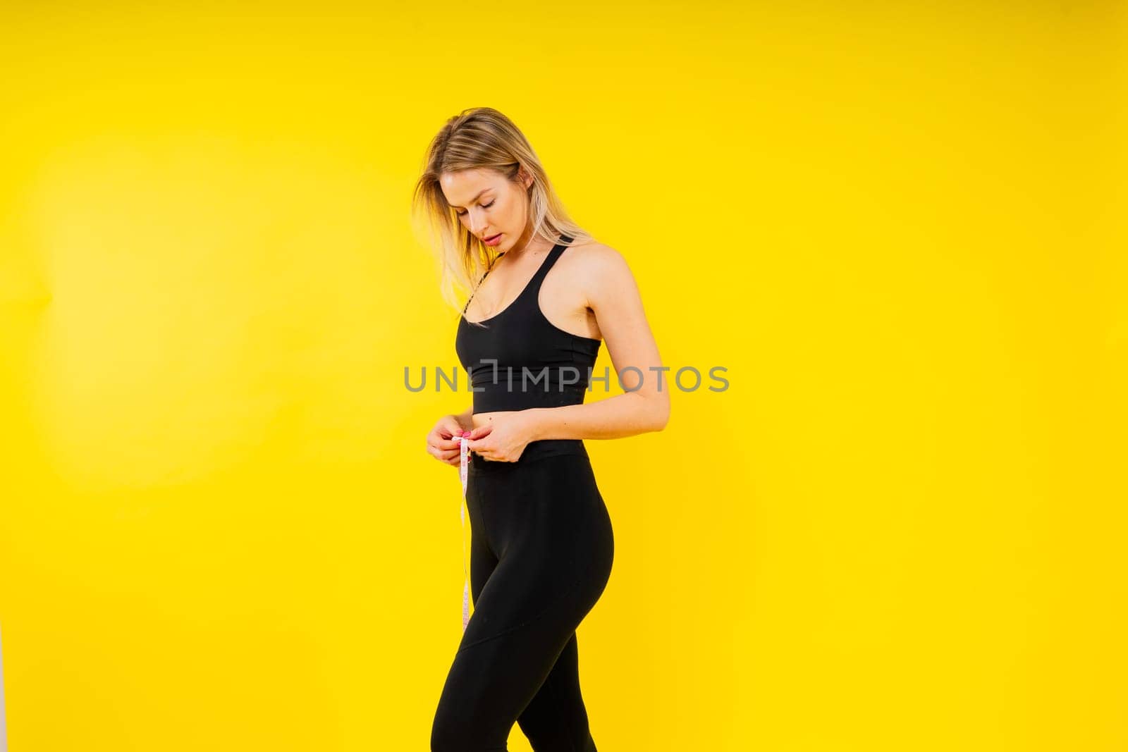 Smiling slim woman measuring her waist with tape. Fit young lady perfect shape, happy her body