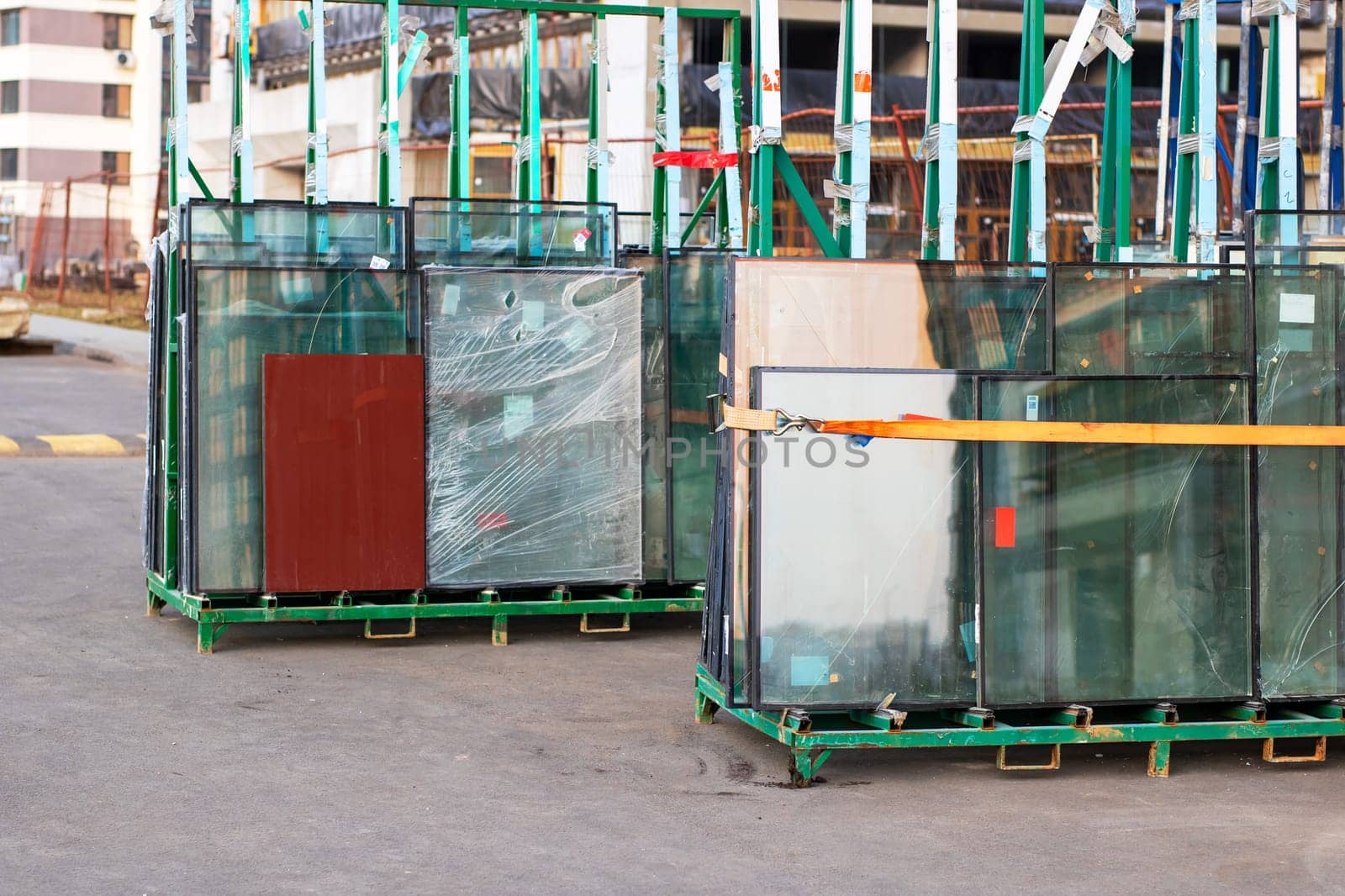 A large number of crates filled with glass are currently positioned on the ground in front of a building that is still under construction