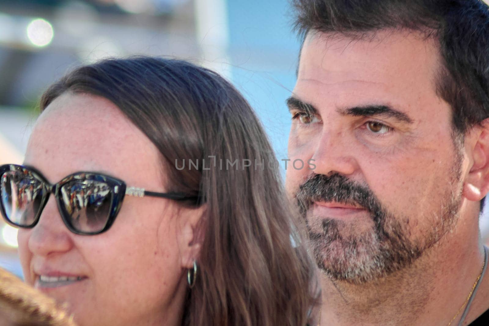 Fashionable man and woman in bold attire and glasses standing outdoors. Captured in a vibrant moment with a blurred natural background.