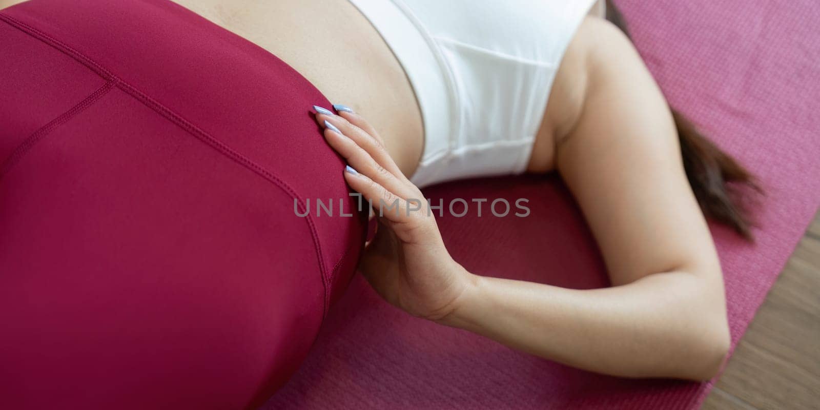 This image highlights a close-up view of a woman adjusting her posture during yoga, showing dedication and focus on her physical fitness.