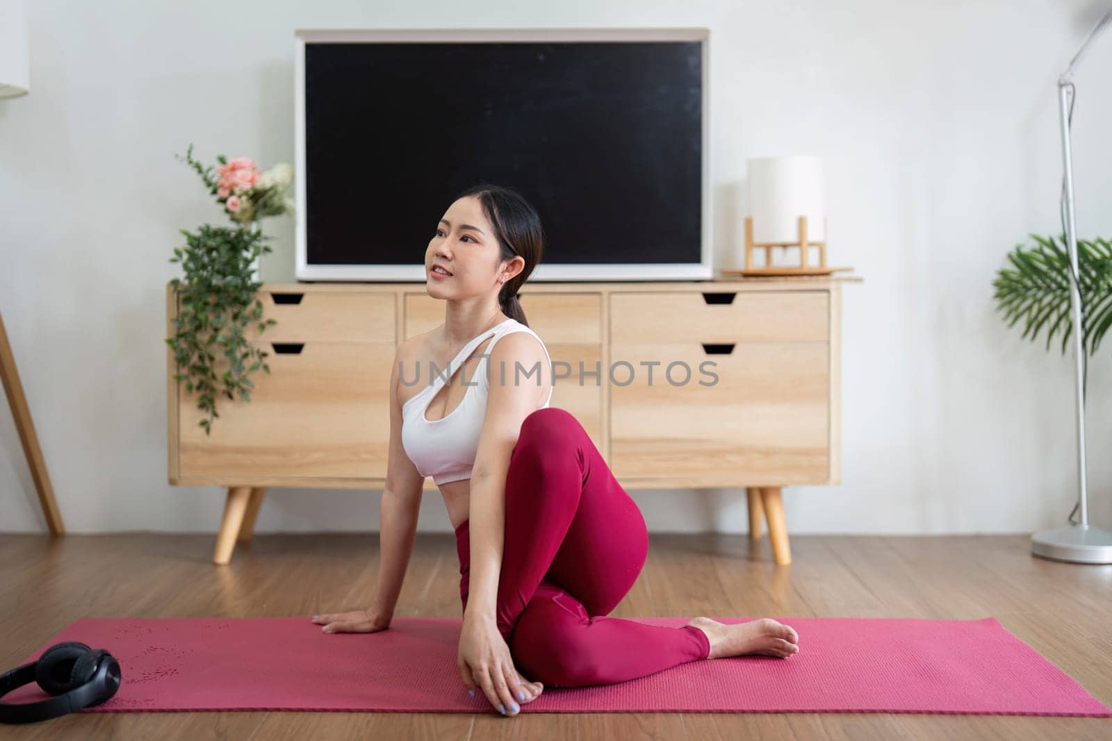 A passionate yogi engages in a twisting pose, focusing on flexibility and strength while enjoying the serenity of her home during practice.