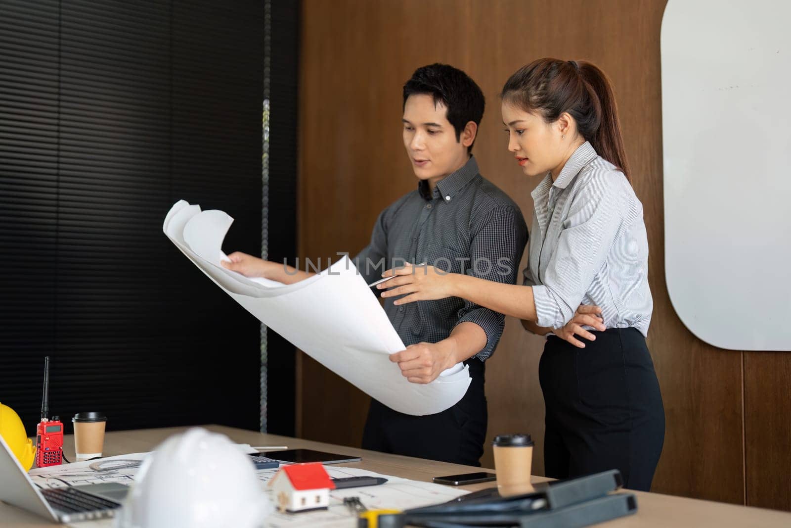 Two engineers share insights over project plans, reflecting collaboration and innovation in their workspace. Their engagement demonstrates teamwork in architectural design.