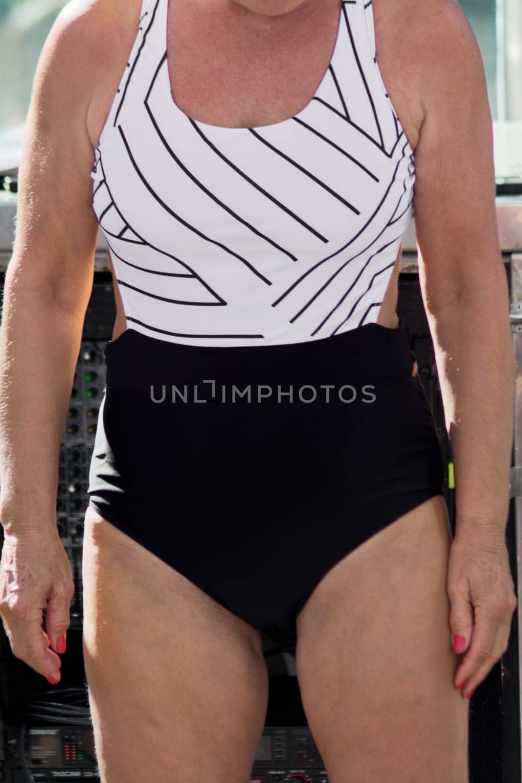 A stylish woman is seen wearing a minimalist one-piece swimsuit. Her poised presence, coupled with the contrast of modern design and vibrant colors, exudes confidence and a relaxed summer aesthetic.