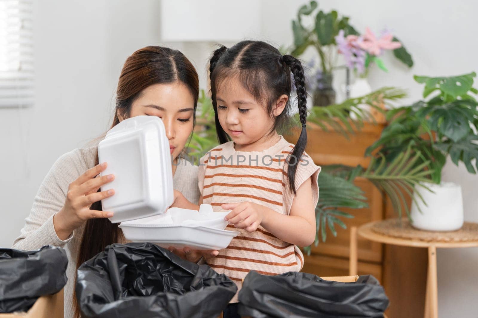 A mother shows her daughter how to reuse takeaway containers, instilling eco-friendly values through fun and creative play at home.