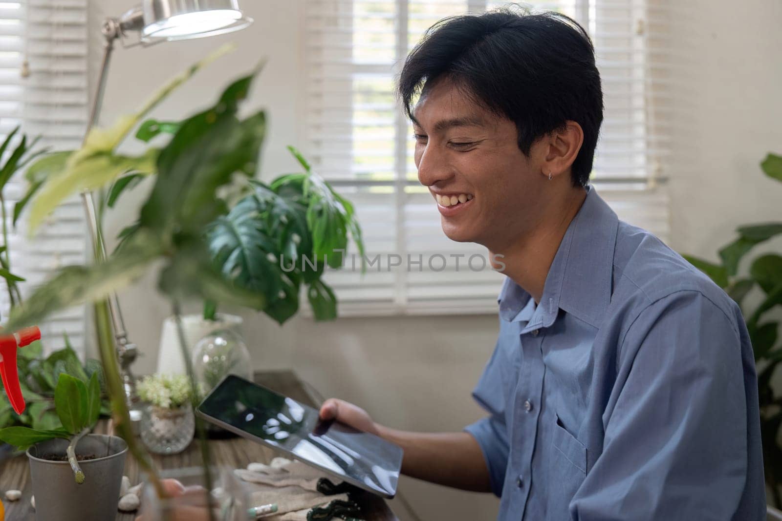 A smiling individual enjoys the process of gardening while using a tablet to enhance his gardening skills, combining joy with technology.