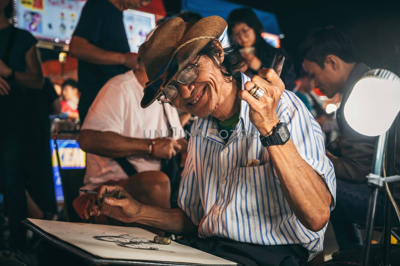 Happy asian male Vietnamese street artist paints portraits on the street in Da Nang in Asia. Da Nang, Vietnam - November 29, 2024