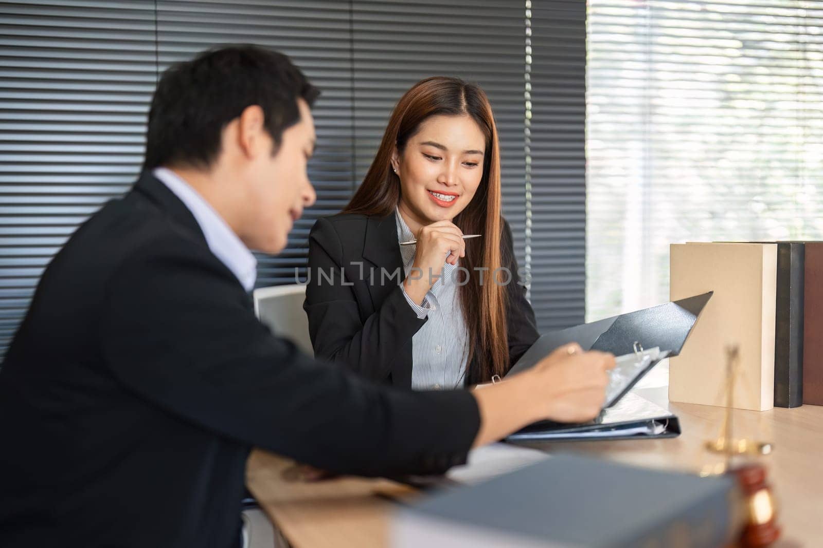 A female client assesses important legal documents while consulting with her lawyer, indicating the collaborative nature of their partnership in navigating legal issues.
