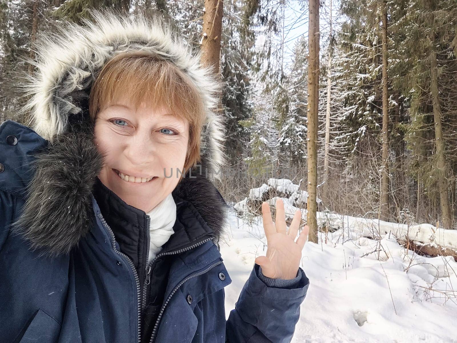 Smiling woman showcases her joyful spirit in a winter forest, capturing a moment of her exciting snowy excursion as a tourist.