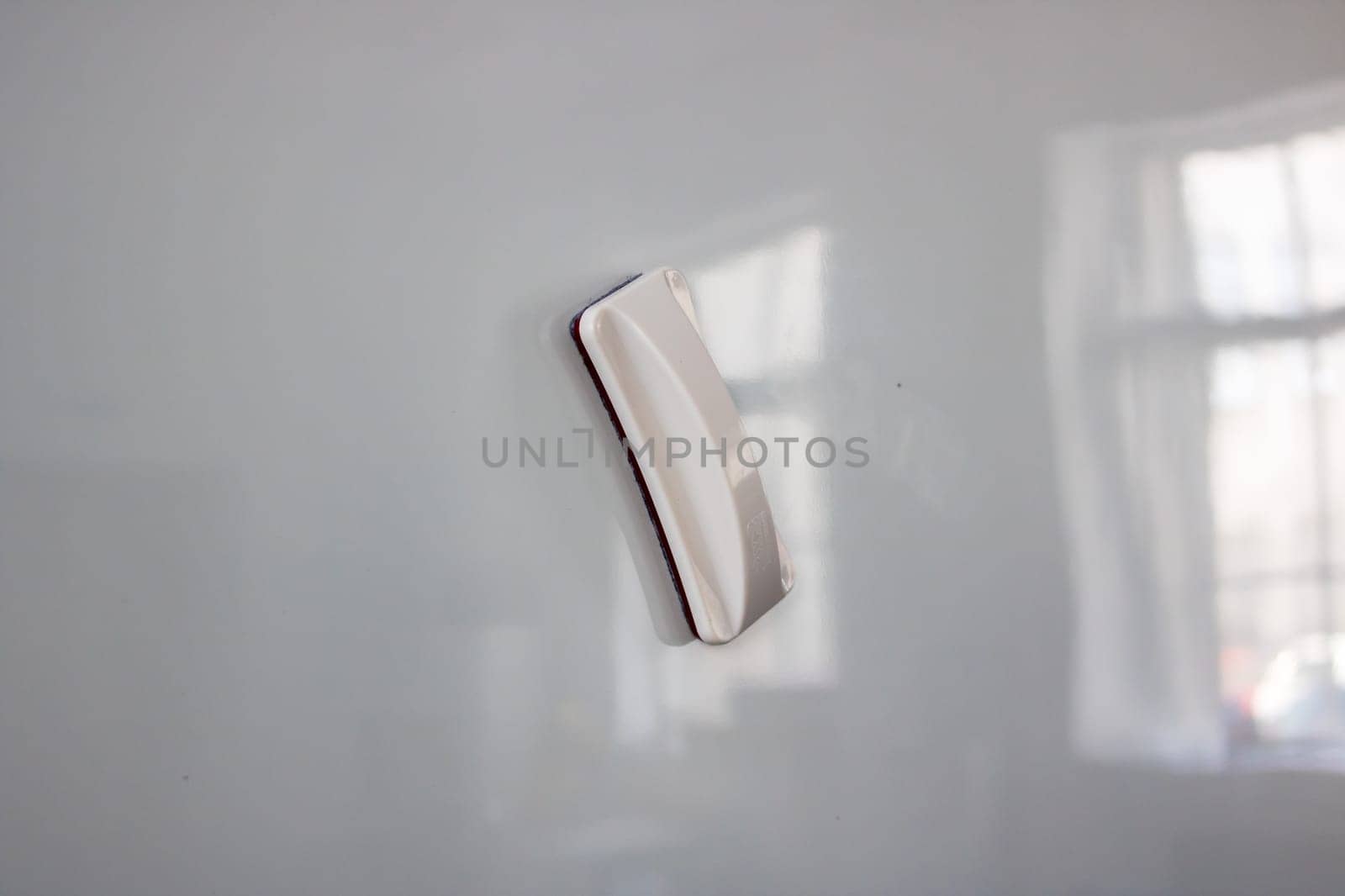 A white board eraser is currently positioned on top of a clean and smooth white board, ready to be used for erasing marks