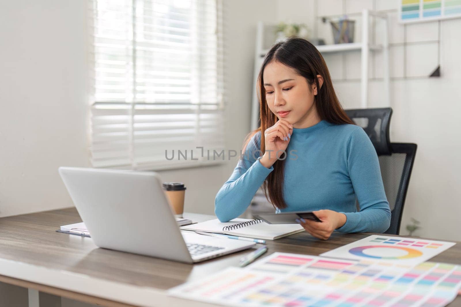 In a serene work environment, a designer is deep in thought, refining her creative strategy and planning next steps for her projects.