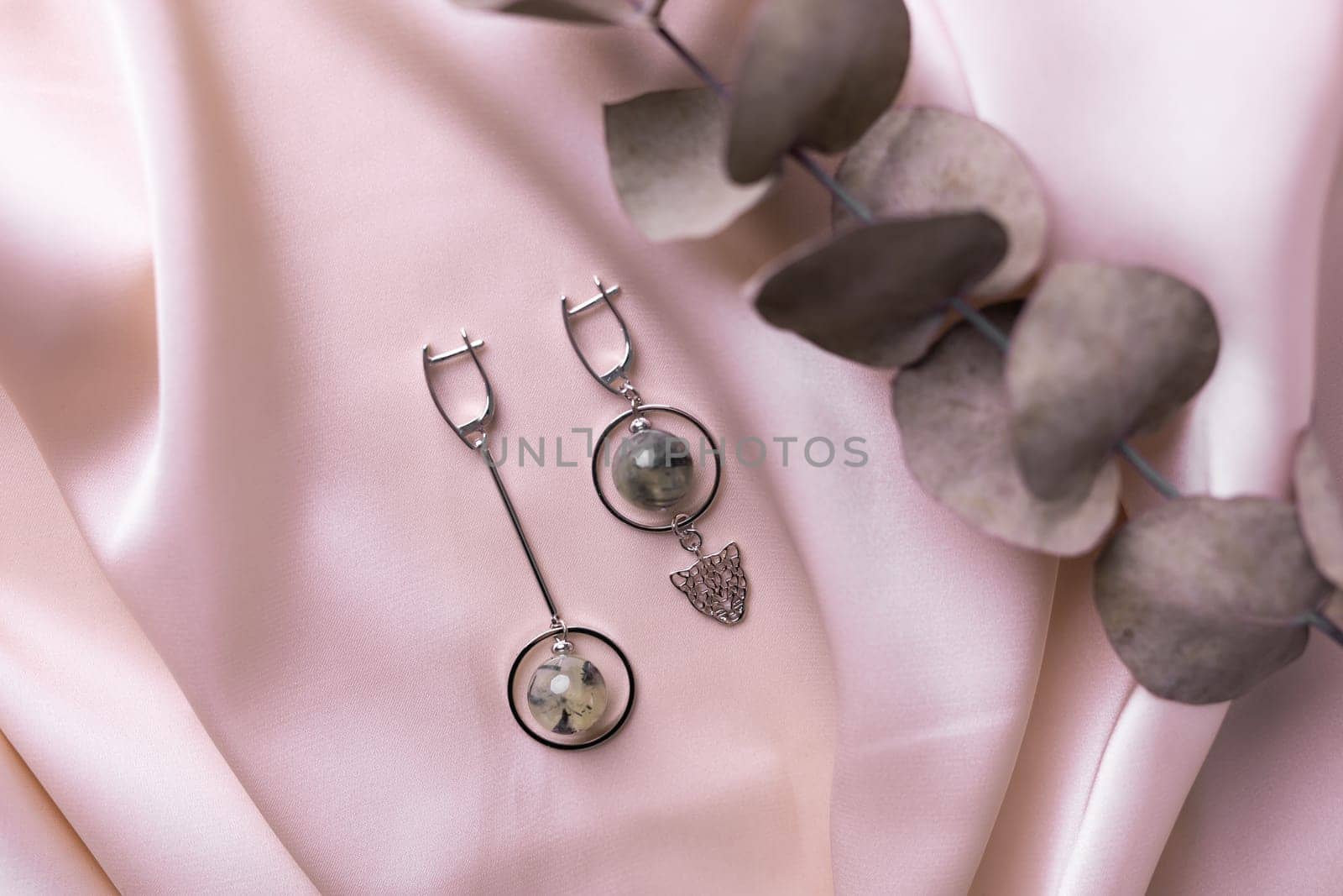 Female Jewelry. Vintage bijouterie jewelry. Beautiful handmade silver earrings on pink silk background. Flat lay, top view copy space and empty space for text.